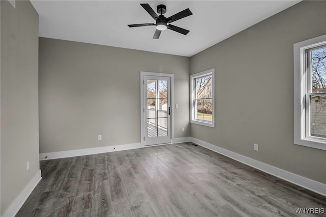 empty room with ceiling fan, a healthy amount of sunlight, and wood-type flooring