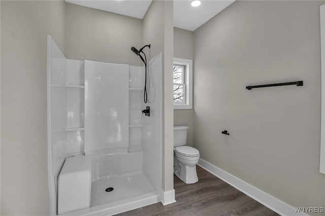 bathroom with hardwood / wood-style flooring, toilet, and a shower