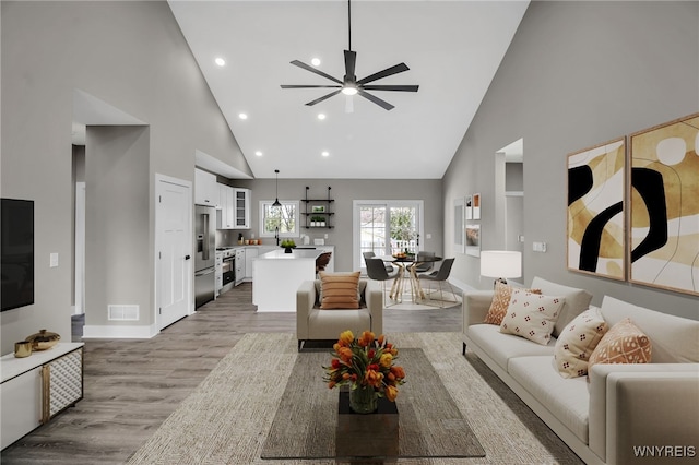 living room featuring ceiling fan, light hardwood / wood-style floors, and high vaulted ceiling