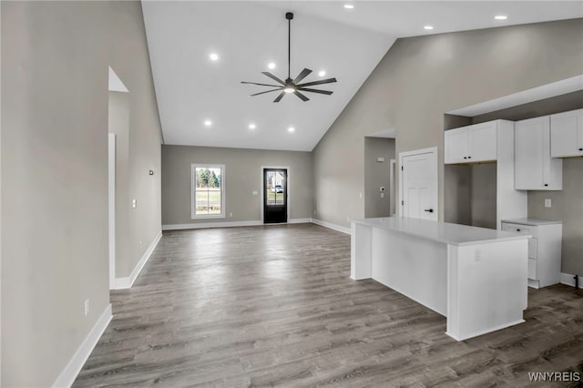 kitchen with a kitchen island, light wood-type flooring, white cabinetry, and high vaulted ceiling