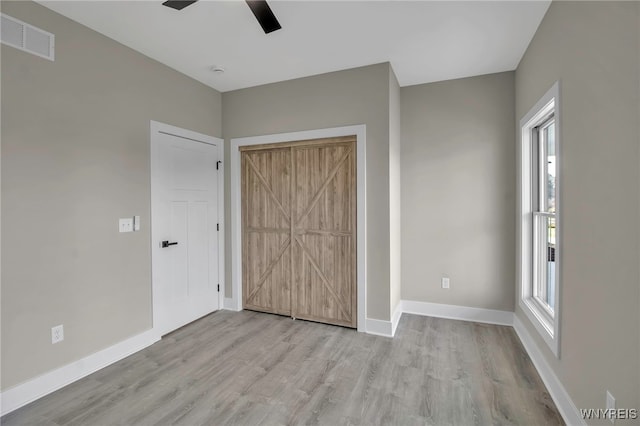 unfurnished bedroom featuring light hardwood / wood-style floors, multiple windows, and ceiling fan