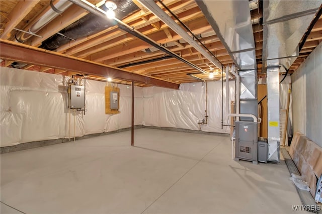 basement featuring electric panel and heating unit