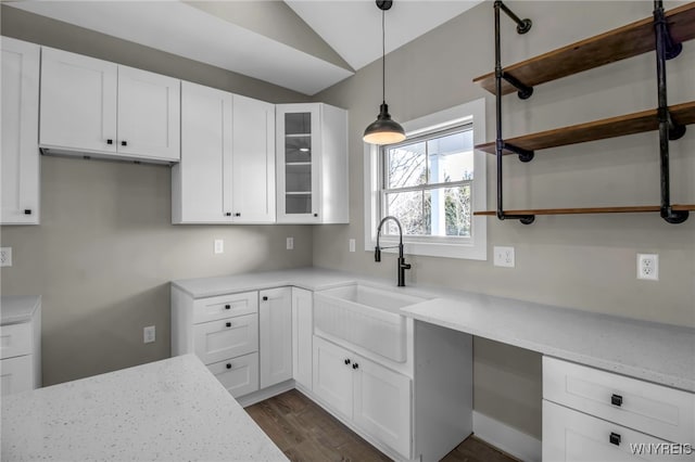 kitchen with white cabinets, light stone countertops, lofted ceiling, and sink