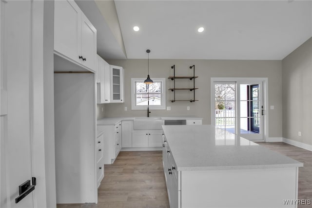 kitchen with hanging light fixtures, light wood-type flooring, white cabinetry, and plenty of natural light