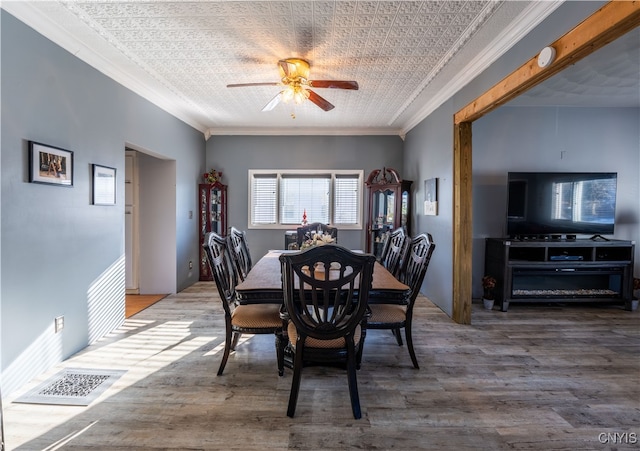 dining room with hardwood / wood-style floors, ceiling fan, ornamental molding, and a textured ceiling