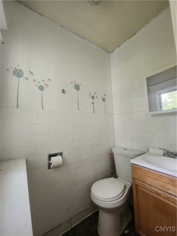 bathroom featuring vanity, tile walls, and toilet