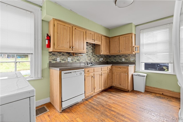 kitchen with light wood-type flooring, white dishwasher, and tasteful backsplash