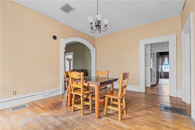 dining space with hardwood / wood-style floors, an inviting chandelier, and crown molding