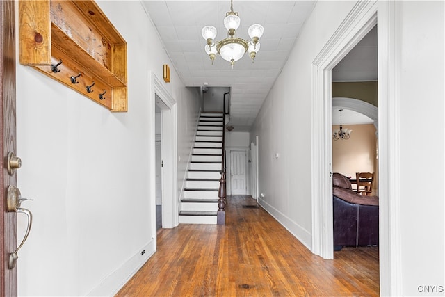 hall with wood-type flooring and an inviting chandelier