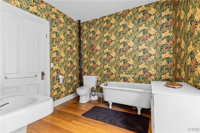 bathroom with toilet, wood-type flooring, and a tub