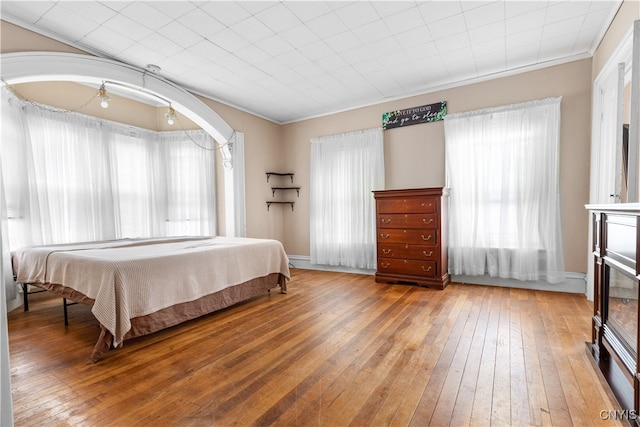 bedroom with wood-type flooring, ornamental molding, and multiple windows