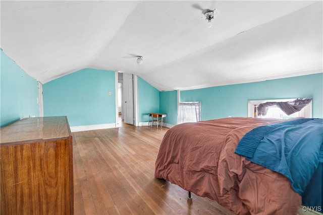 bedroom with hardwood / wood-style flooring, lofted ceiling, and multiple windows