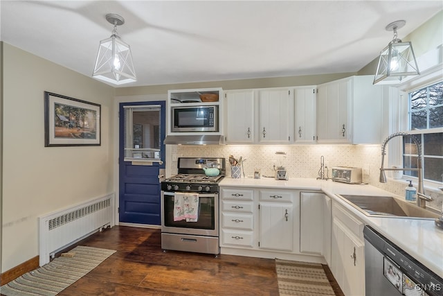 kitchen featuring white cabinets, decorative light fixtures, radiator, and appliances with stainless steel finishes