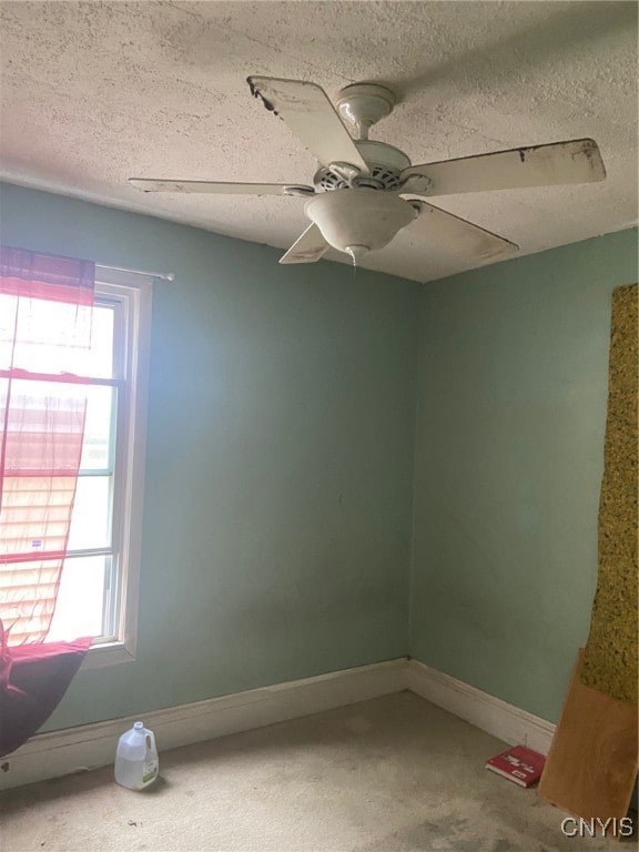 spare room with a textured ceiling, ceiling fan, and a healthy amount of sunlight