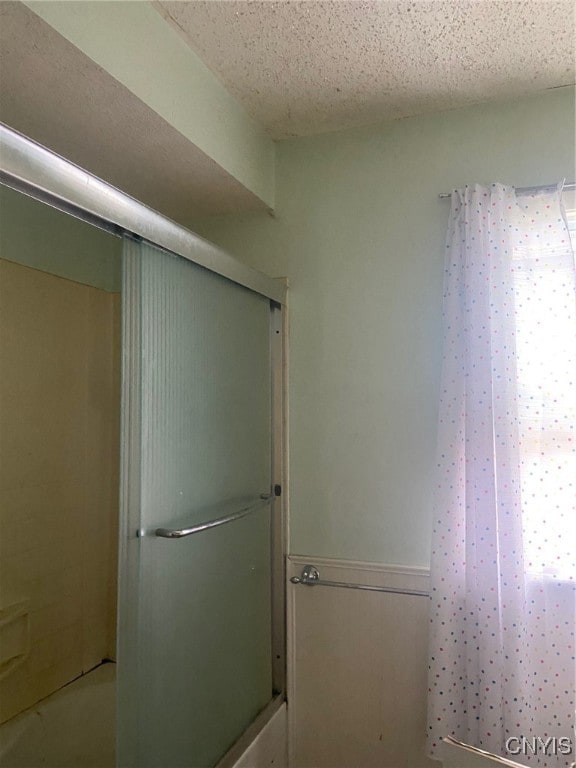 bathroom with a textured ceiling and tub / shower combination