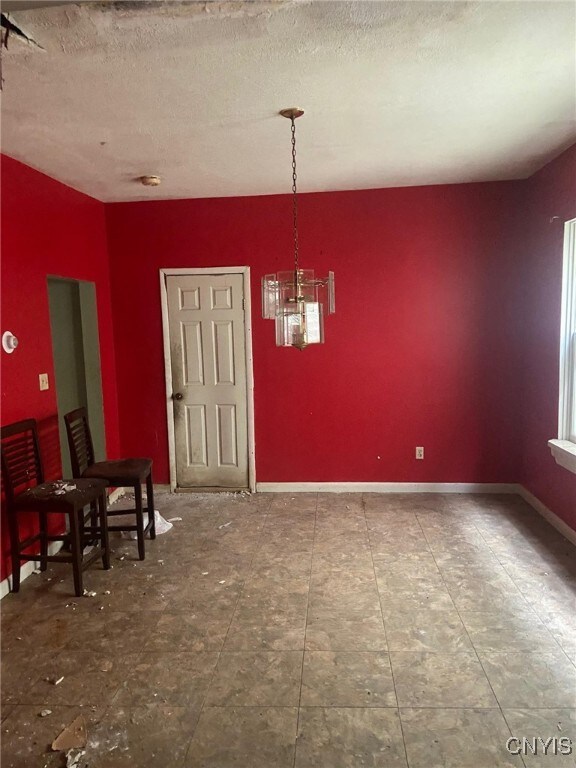 unfurnished dining area with a notable chandelier and a textured ceiling