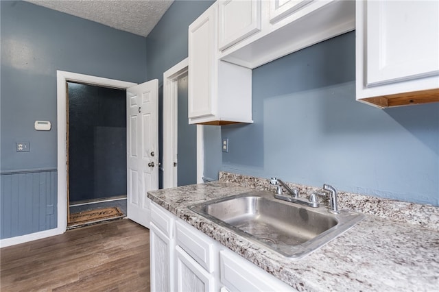 kitchen with a textured ceiling, sink, white cabinets, and dark hardwood / wood-style floors