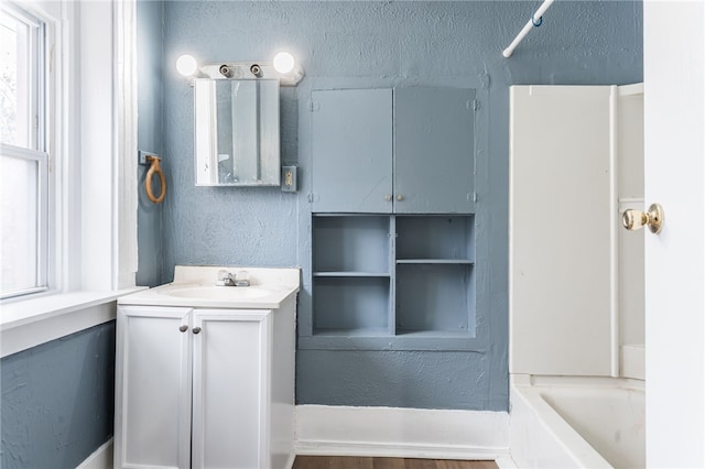 bathroom with washtub / shower combination, vanity, and hardwood / wood-style flooring