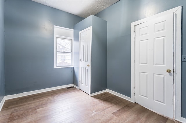 unfurnished bedroom featuring hardwood / wood-style floors and a textured ceiling