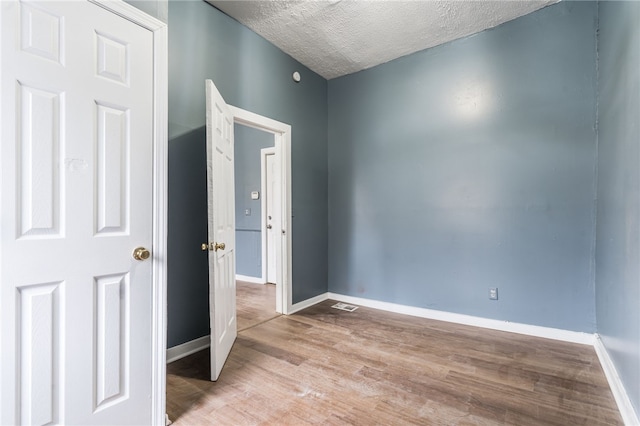 spare room with a textured ceiling and light wood-type flooring