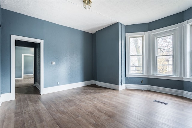 spare room featuring a textured ceiling and hardwood / wood-style flooring