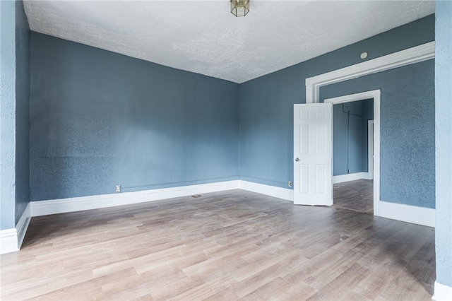 empty room with hardwood / wood-style flooring and a textured ceiling