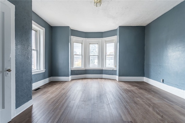 spare room with dark hardwood / wood-style floors, a healthy amount of sunlight, and a textured ceiling