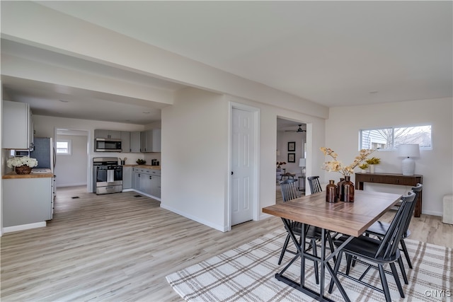 dining space with ceiling fan and light wood-type flooring