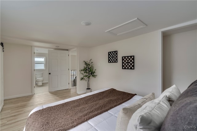 bedroom featuring connected bathroom and light hardwood / wood-style flooring