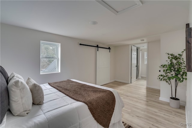 bedroom featuring a barn door and light hardwood / wood-style floors