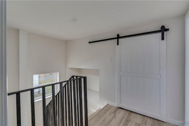 hallway featuring a barn door and light hardwood / wood-style flooring