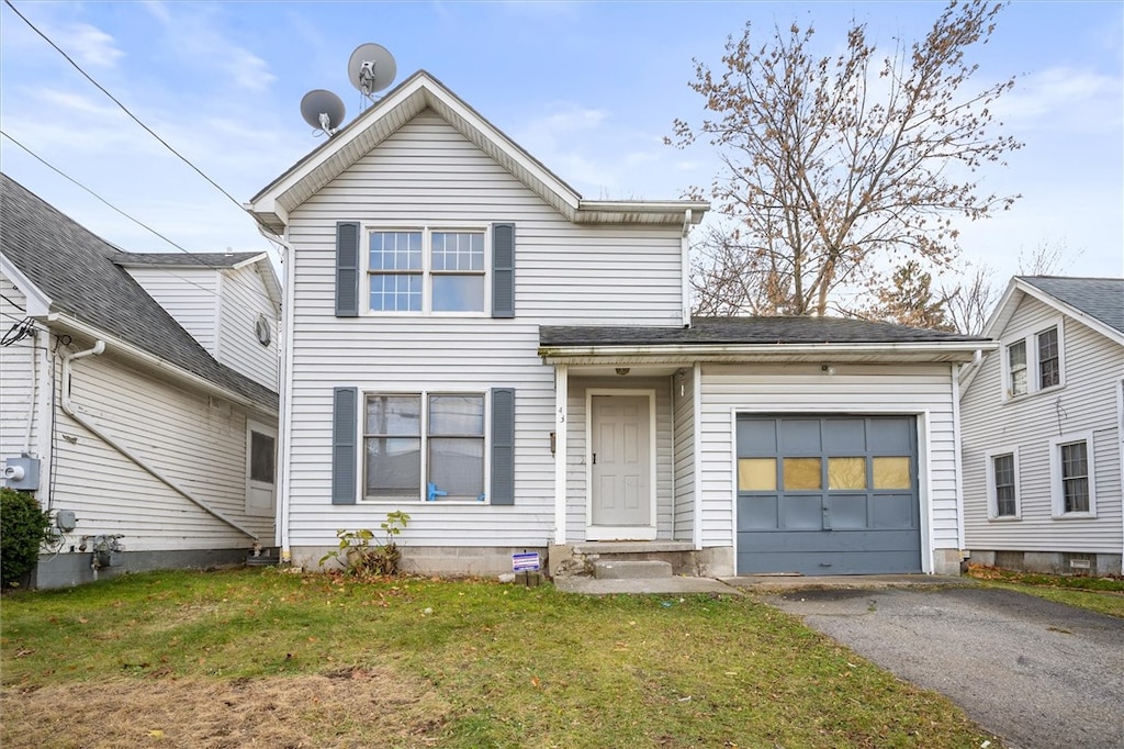 view of property featuring a garage and a front lawn