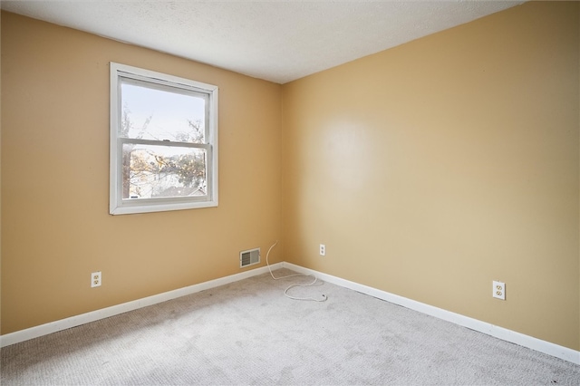 carpeted empty room featuring a textured ceiling