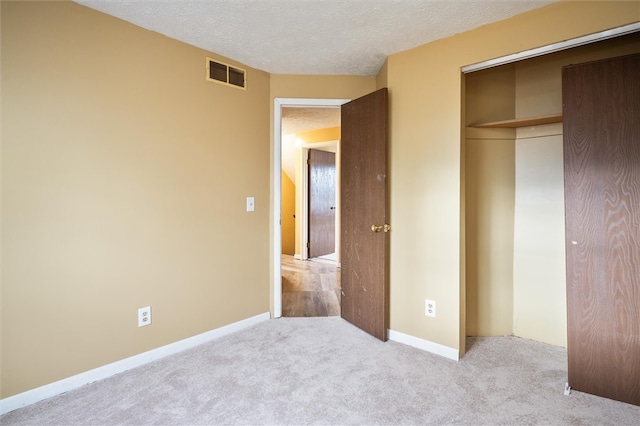 unfurnished bedroom with light carpet, a closet, and a textured ceiling