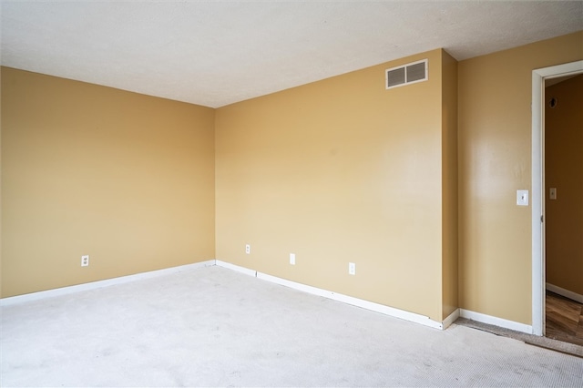 empty room with a textured ceiling and light colored carpet