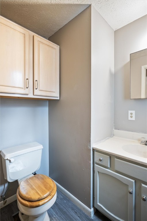 bathroom featuring vanity, hardwood / wood-style floors, a textured ceiling, and toilet