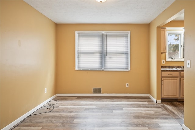 spare room featuring light hardwood / wood-style flooring and a textured ceiling