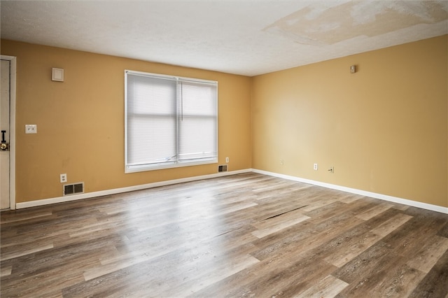 spare room featuring hardwood / wood-style floors and a textured ceiling