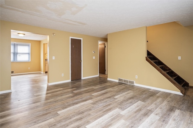 unfurnished living room featuring wood-type flooring and a textured ceiling