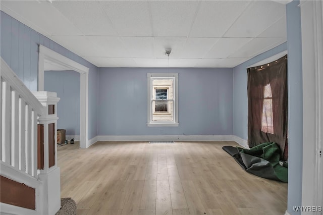 interior space with a paneled ceiling and light hardwood / wood-style flooring