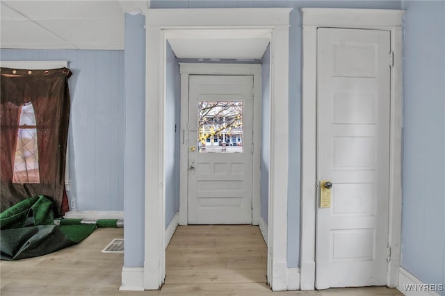 doorway to outside with light hardwood / wood-style floors and wood walls