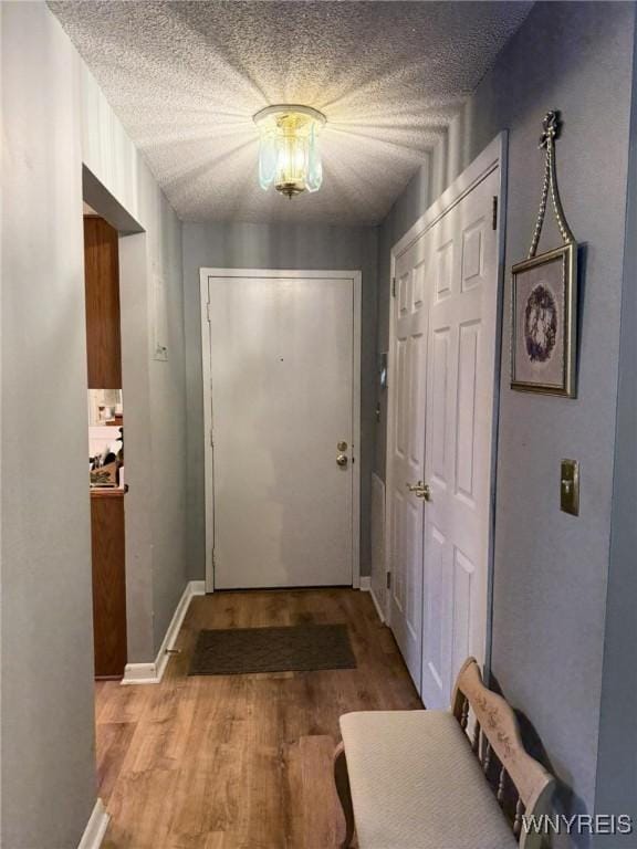 doorway featuring light wood-type flooring and a textured ceiling