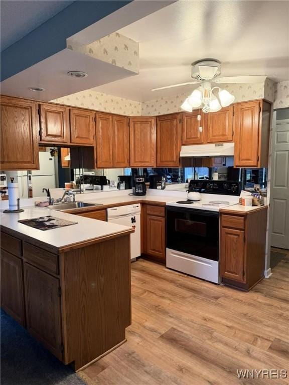 kitchen with kitchen peninsula, white appliances, light hardwood / wood-style flooring, and sink