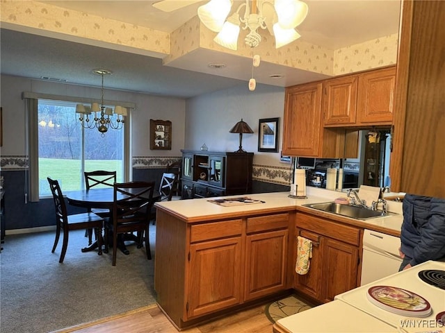 kitchen with ceiling fan with notable chandelier, sink, light hardwood / wood-style flooring, decorative light fixtures, and kitchen peninsula