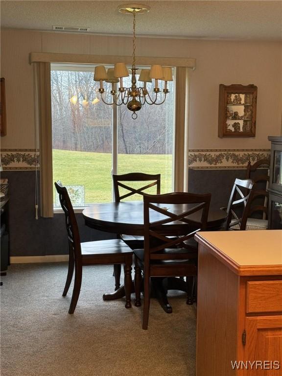 dining room featuring light colored carpet, a textured ceiling, and an inviting chandelier