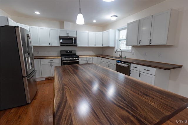 kitchen featuring butcher block counters, sink, dark hardwood / wood-style flooring, white cabinets, and appliances with stainless steel finishes