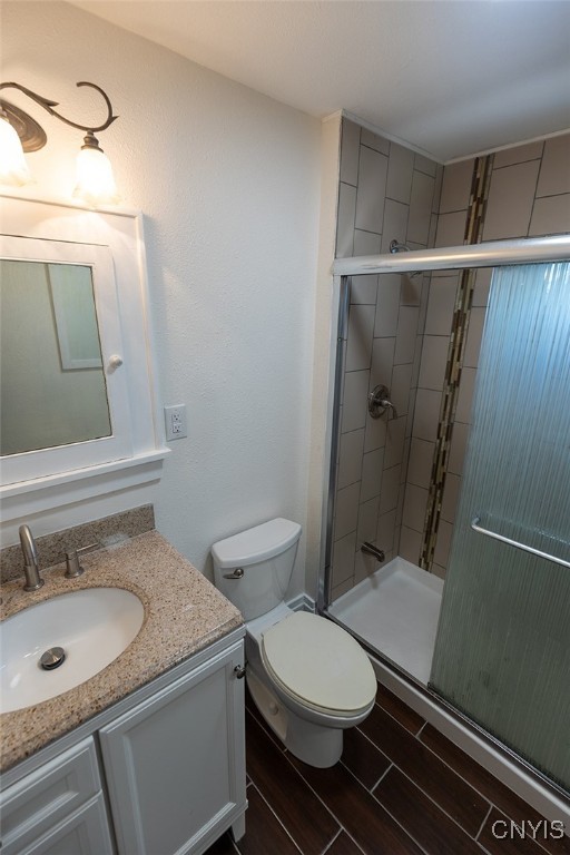 bathroom featuring vanity, toilet, and a shower with door