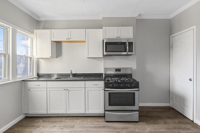 kitchen featuring white cabinets, appliances with stainless steel finishes, light hardwood / wood-style flooring, and sink