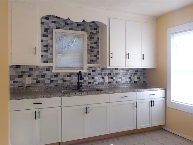 kitchen featuring backsplash, sink, white cabinets, and light tile patterned flooring