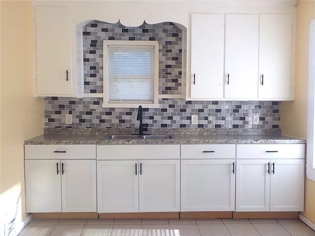 kitchen with white cabinets, light tile patterned floors, tasteful backsplash, and sink